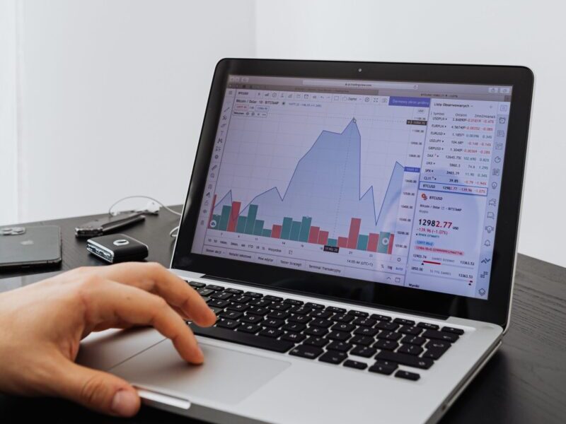 A person analyzing financial data on a laptop with graphs displayed on the screen.